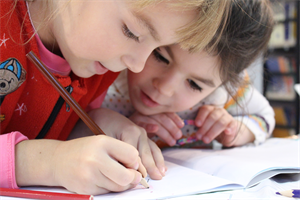 Zwei Kinder lösen gemeinsam eine Schulaufgabe